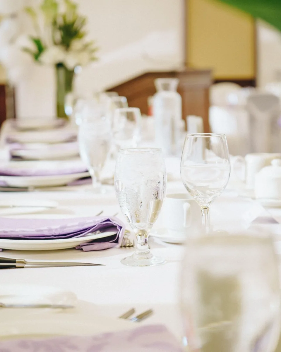 Table dressée sur nappe claire avec verrerie, photo d’illustration