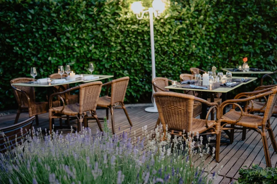 Terrasse avec fauteuils en rotin et tables dressées, photo d’illustration